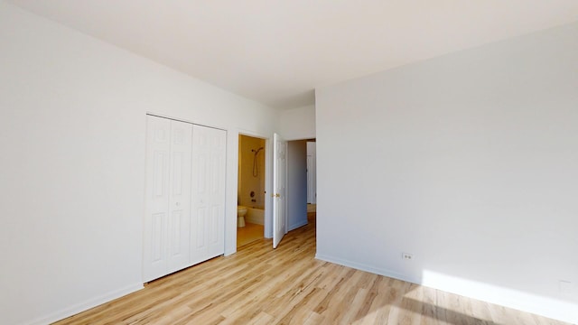 unfurnished bedroom with light wood-style flooring, baseboards, and a closet