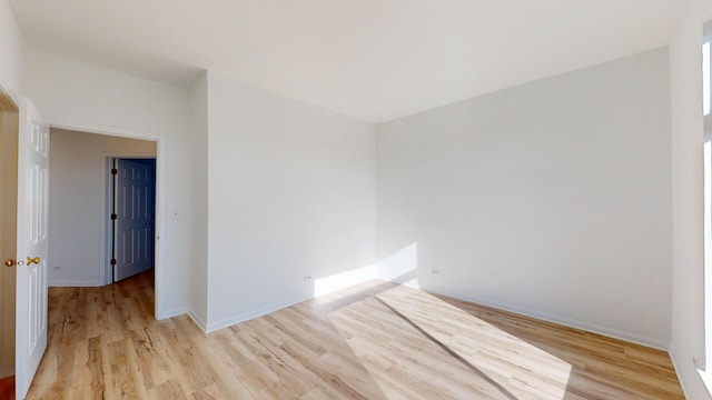 spare room featuring baseboards and light wood-style floors