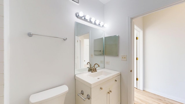 bathroom with toilet, vanity, and wood finished floors