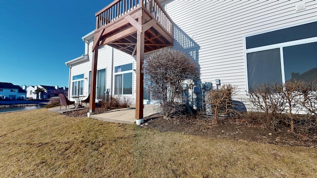 view of side of home with a patio, a lawn, and a water view