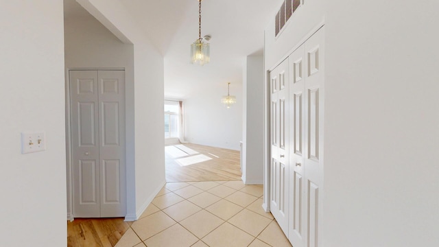 hall with light tile patterned floors, baseboards, and visible vents