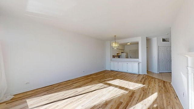 unfurnished room with a notable chandelier, light wood-style floors, and visible vents