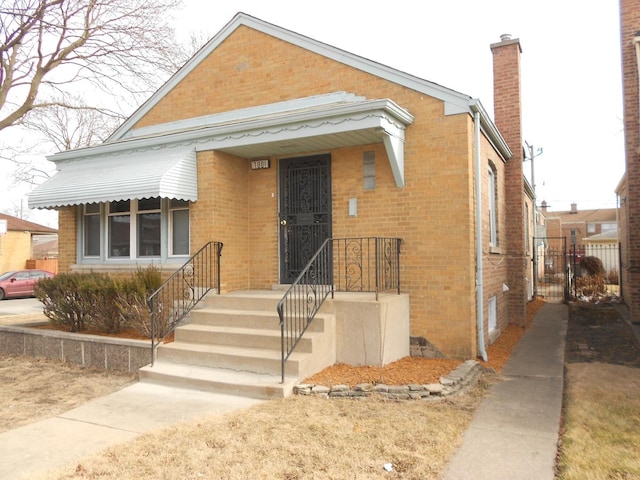 view of front of home with a chimney and brick siding