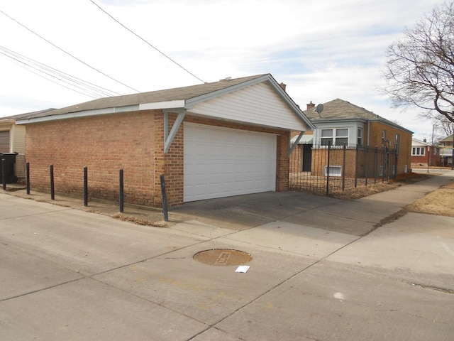 view of side of property featuring a garage, fence, an outdoor structure, and brick siding