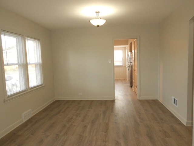 unfurnished room with baseboards, visible vents, and wood finished floors