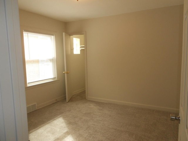 unfurnished room with light carpet, visible vents, and baseboards