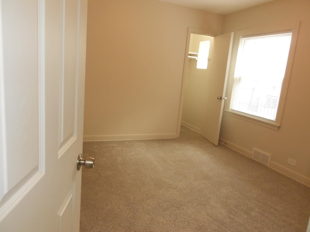 unfurnished room with carpet flooring, visible vents, and baseboards