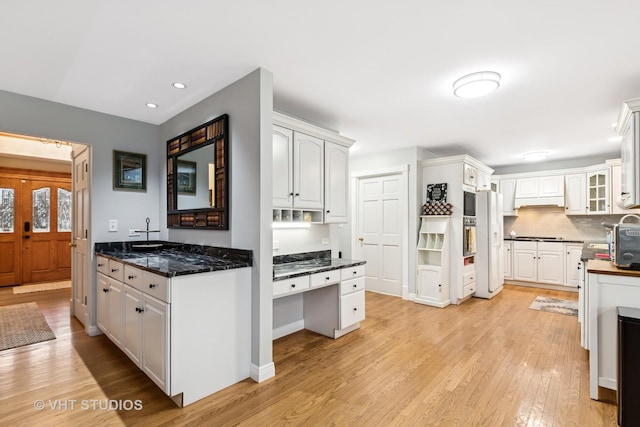 kitchen featuring white refrigerator with ice dispenser, backsplash, light wood-style flooring, glass insert cabinets, and white cabinets