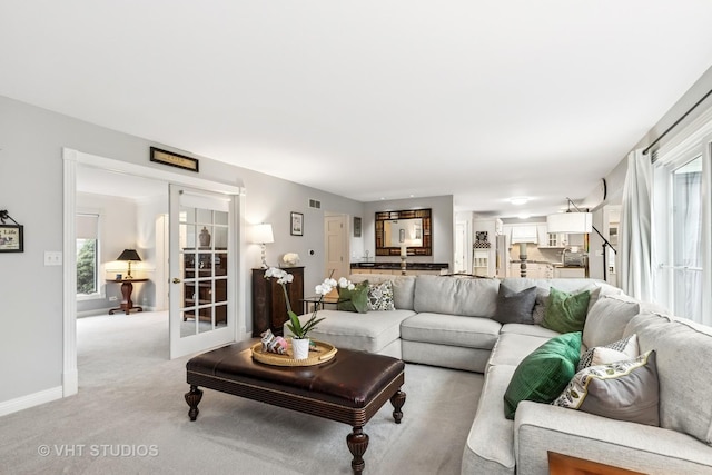 living room with french doors, light carpet, visible vents, and baseboards