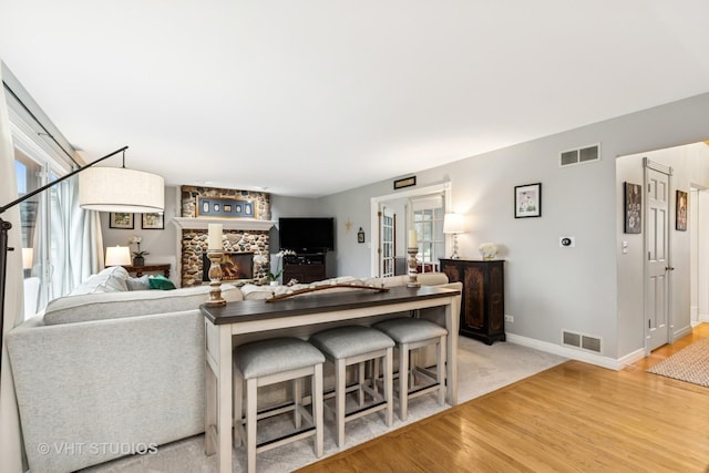 living area with light wood-type flooring, visible vents, and a wealth of natural light