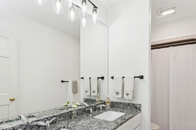 bathroom with double vanity, visible vents, a shower with shower curtain, toilet, and a sink