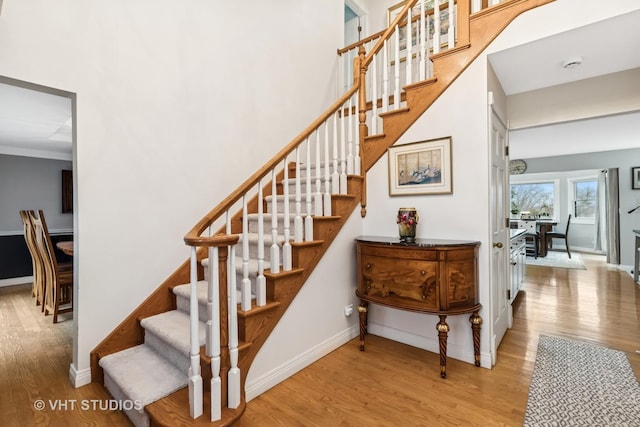 stairs featuring a high ceiling, baseboards, and wood finished floors