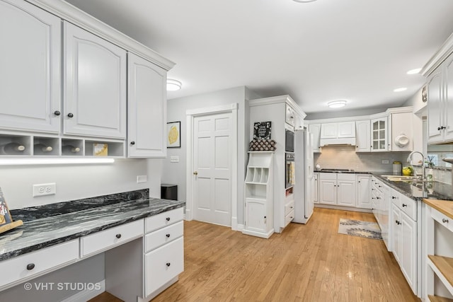 kitchen with gas cooktop, a sink, white cabinetry, light wood-style floors, and decorative backsplash