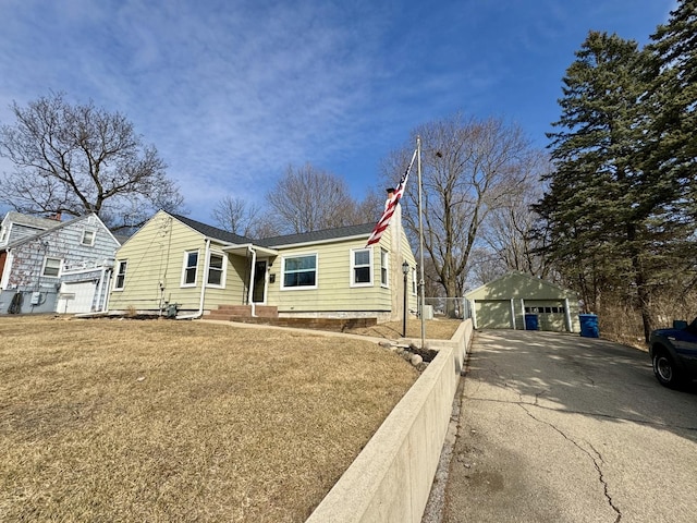 view of front facade with a garage, an outbuilding, fence, and a front lawn