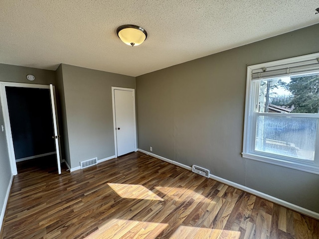 unfurnished bedroom with wood finished floors, visible vents, and baseboards