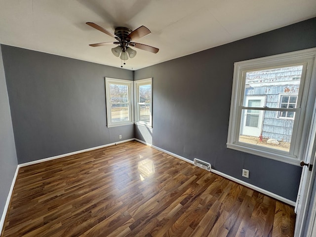 unfurnished room with ceiling fan, wood finished floors, visible vents, and baseboards