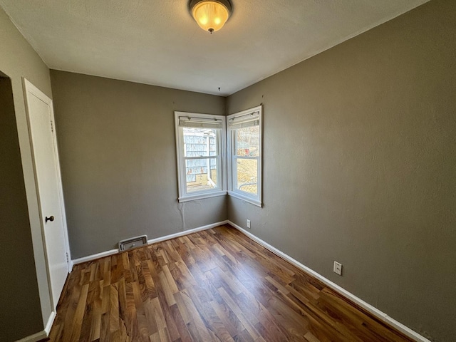 spare room with baseboards and wood finished floors