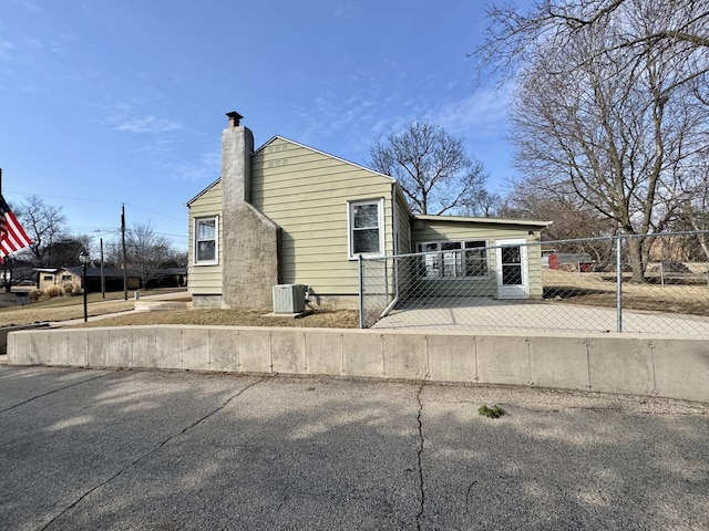 view of front of home with a fenced front yard, cooling unit, and a chimney