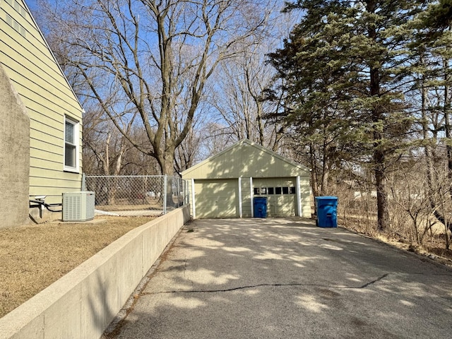 view of property exterior featuring central AC, an outdoor structure, fence, and a detached garage