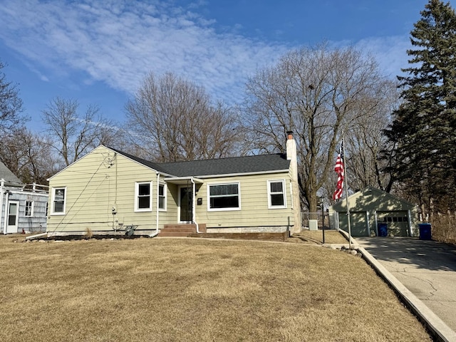 view of front of property with a garage, a chimney, an outdoor structure, and a front yard