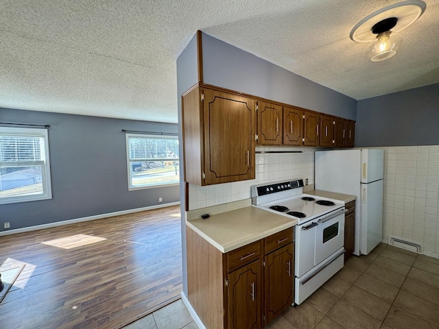 kitchen featuring visible vents, light countertops, a textured ceiling, wood finished floors, and white appliances