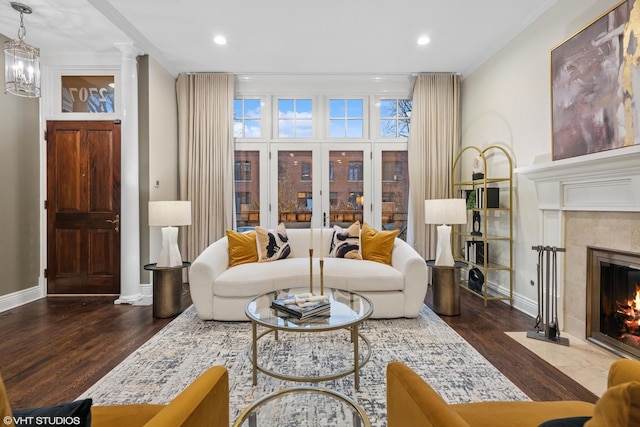 living area featuring a fireplace, wood finished floors, decorative columns, and baseboards