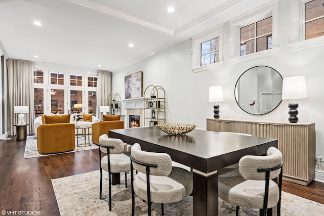 dining space featuring ornamental molding, recessed lighting, dark wood finished floors, and a lit fireplace