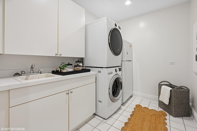 laundry room featuring light tile patterned floors, recessed lighting, stacked washer and dryer, a sink, and cabinet space