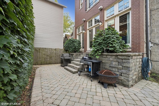 view of patio with an outdoor fire pit, a grill, and fence