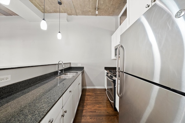 kitchen featuring dark wood-type flooring, a sink, white cabinetry, appliances with stainless steel finishes, and dark stone counters