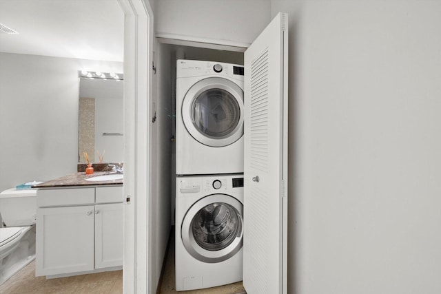 washroom with laundry area, visible vents, a sink, and stacked washing maching and dryer