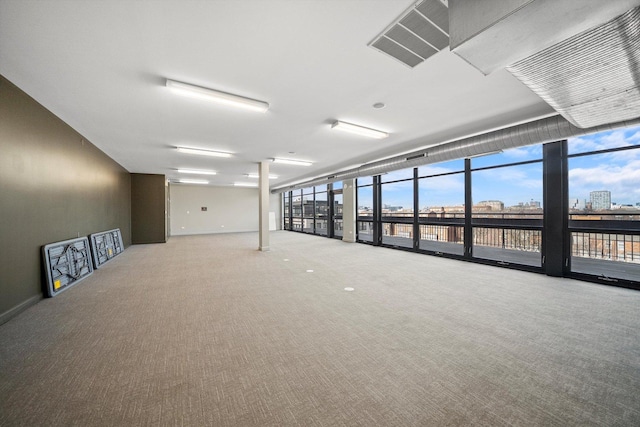 carpeted empty room with visible vents, a wall of windows, and a city view