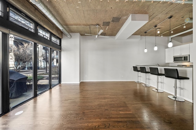 kitchen featuring baseboards, a high ceiling, stainless steel microwave, and dark wood finished floors