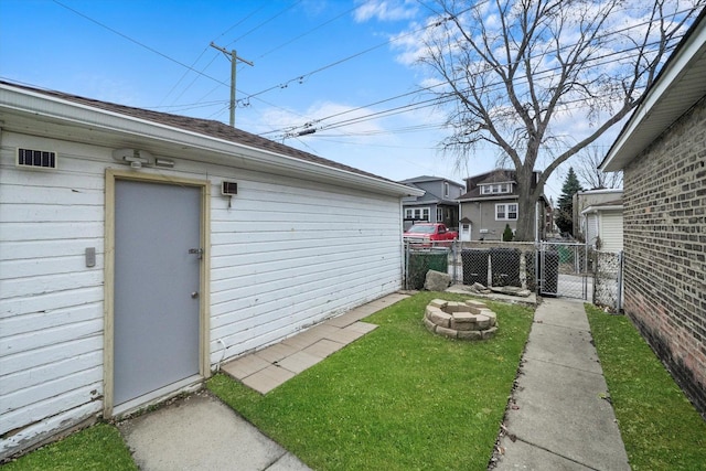 view of yard featuring a fire pit, a gate, fence, and an outbuilding