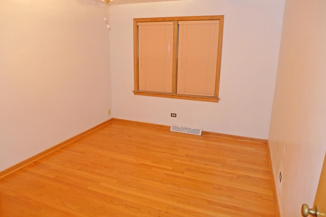 unfurnished room featuring wood finished floors, visible vents, and baseboards