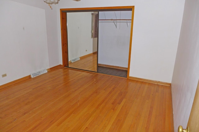 unfurnished bedroom featuring light wood-type flooring, a closet, visible vents, and baseboards