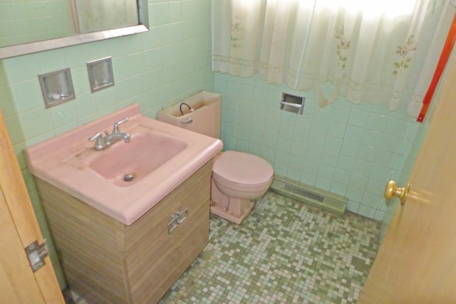 half bath with tile patterned flooring, toilet, visible vents, vanity, and tile walls