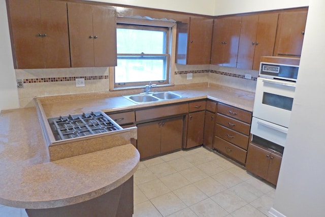 kitchen with tasteful backsplash, white oven, a sink, light countertops, and a warming drawer