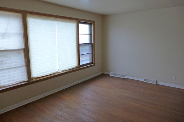 spare room with visible vents, baseboards, and wood finished floors