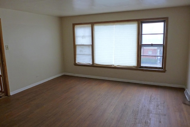 spare room featuring baseboards and wood finished floors