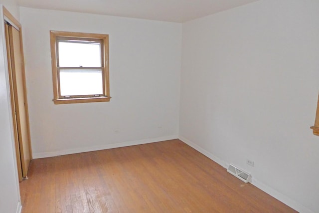 spare room featuring visible vents, light wood-style flooring, and baseboards