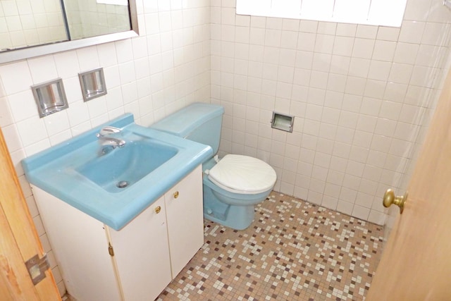 half bath featuring toilet, tile patterned flooring, tile walls, and vanity