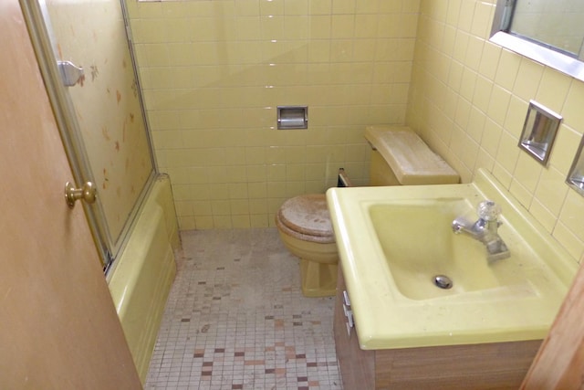 full bathroom featuring tile patterned flooring, a sink, tile walls, and toilet