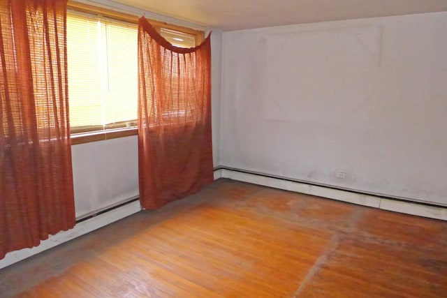 unfurnished room with a baseboard heating unit and wood finished floors