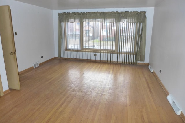 spare room with baseboards, visible vents, and wood finished floors