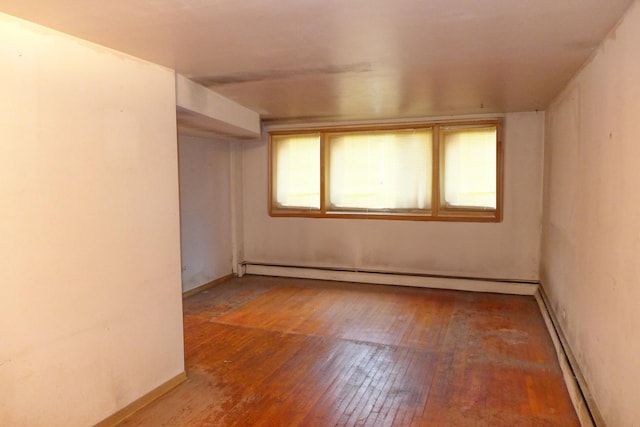 unfurnished room with a baseboard heating unit, baseboard heating, and hardwood / wood-style flooring