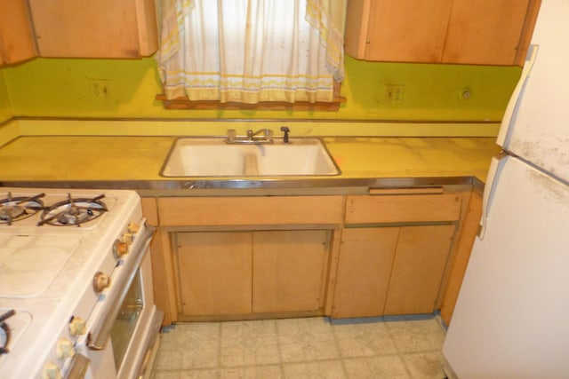 kitchen featuring light countertops, white appliances, and a sink