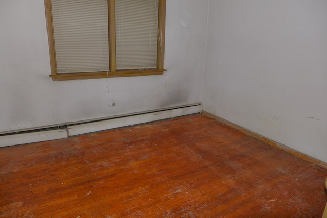 spare room featuring a baseboard radiator, hardwood / wood-style flooring, and baseboards