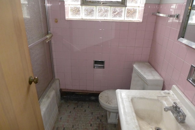 full bathroom featuring toilet, a sink, tile walls, and tile patterned floors