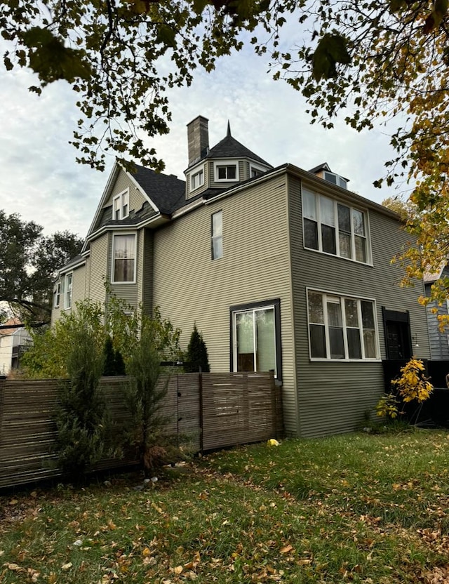 rear view of house featuring a yard and fence